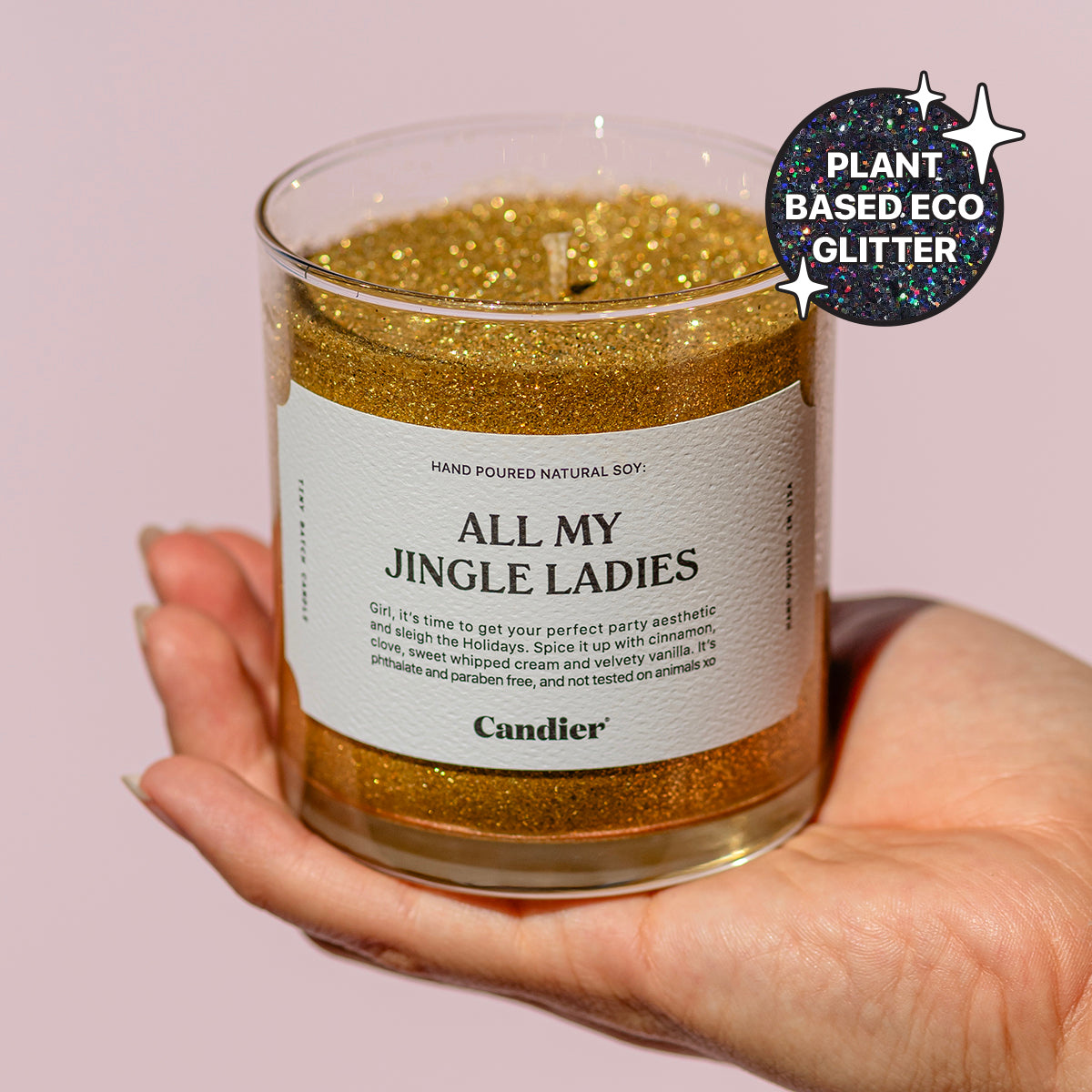 A woman holding a shining sparkly gold Christmas themed scented candle with a label that reads ALL MY JINGLE LADIES by Candier and a badge that says Plant Based Eco Glitter