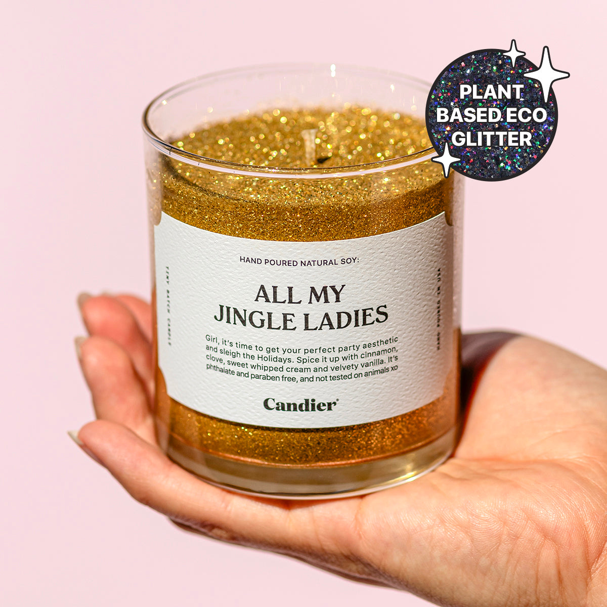 A woman holding a shining sparkly gold Christmas themed scented candle with a label that reads ALL MY JINGLE LADIES by Candier and a badge that says Plant Based Eco Glitter