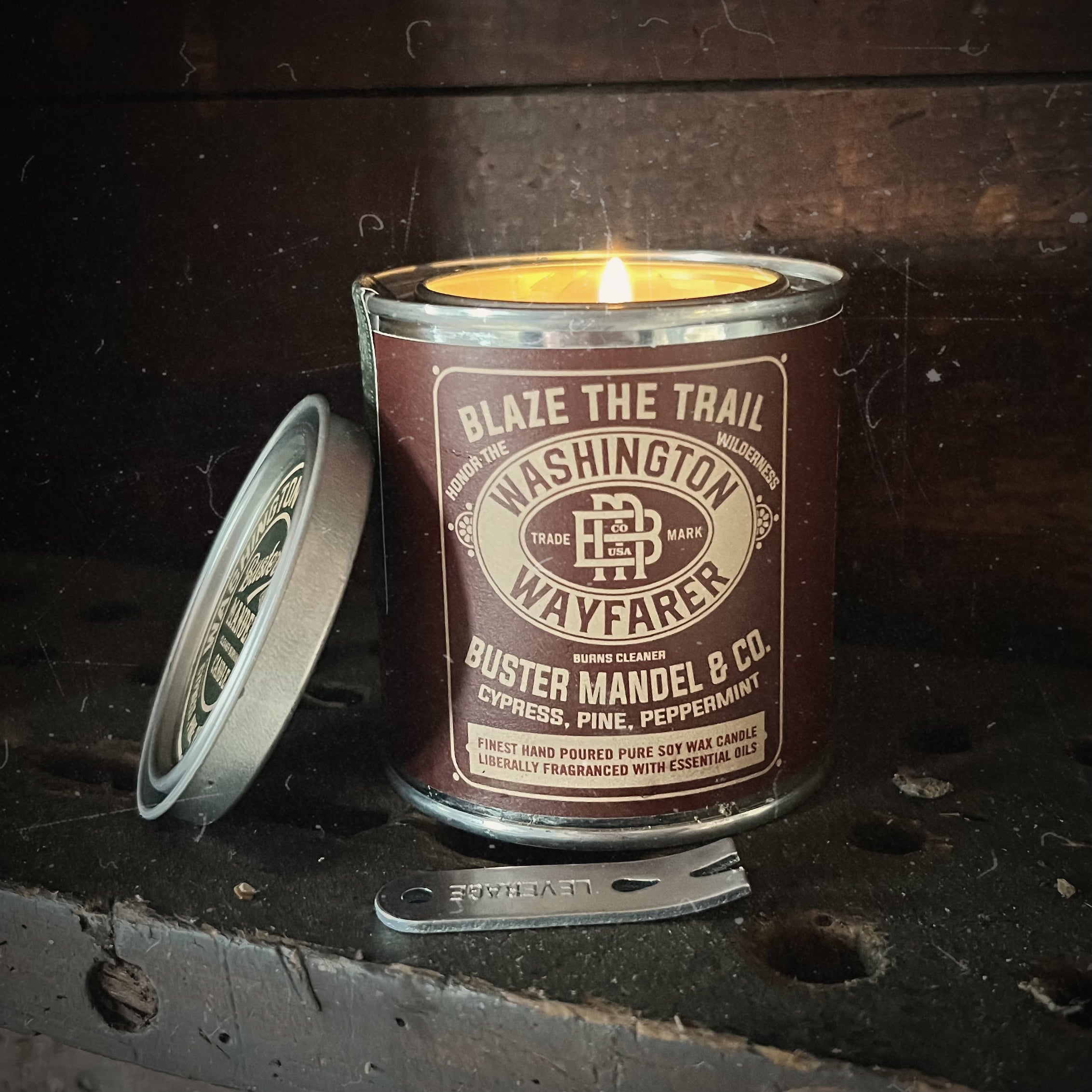 Buster Mandel’s rugged, vintage-inspired luxury candle for men, Washington Wayfarer, burning inside a cozy cabin. A premium gift for men featuring a smoky, woodsy fragrance of cypress, pine, and tonka bean.