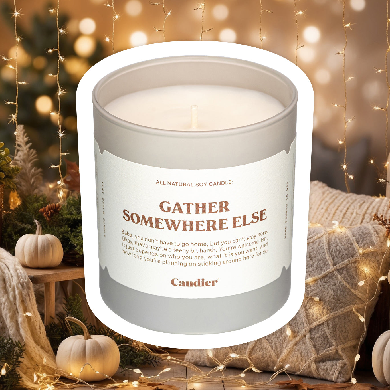 A luxe fall scented candle with a label that reads Gather Somewhere Else, with a trendy background of fashionable autumn decor