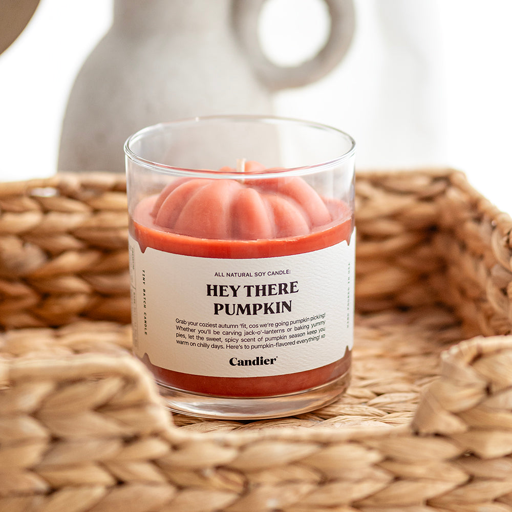 A cute pumpkin shaped candle with a label that reads Hey There Pumpkin