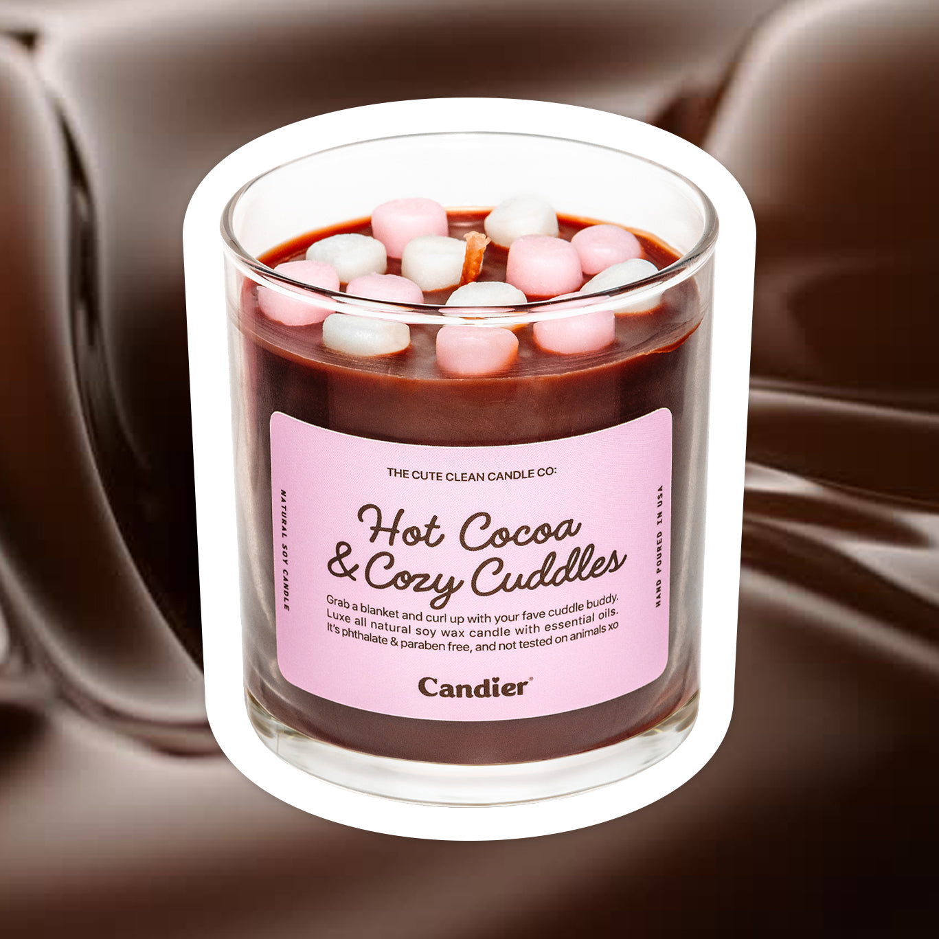 A cute pink candle that is hot chocolate themed with mini wax marshmallows and a label that reads Hot Cocoa & Cozy Cuddles by Candier® candles, with a rich melted chocolate background 