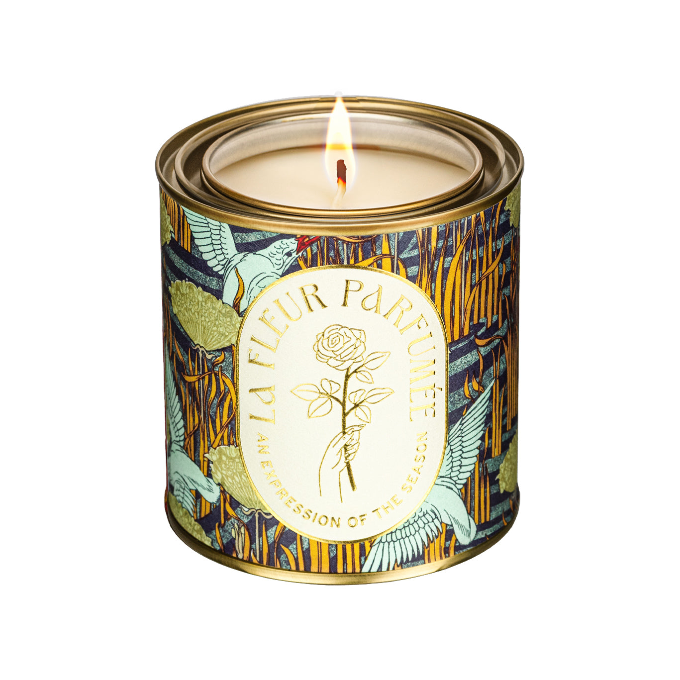 A luxury scented candle with a bold seasonal, fall, nature inspired pattern, of birds by the river with a crisp white label and gold writing that reads LA FLEUR PARFUMÉE: An Expression of the Season, and an illustration of a hand holding an elegant rose by the stem.