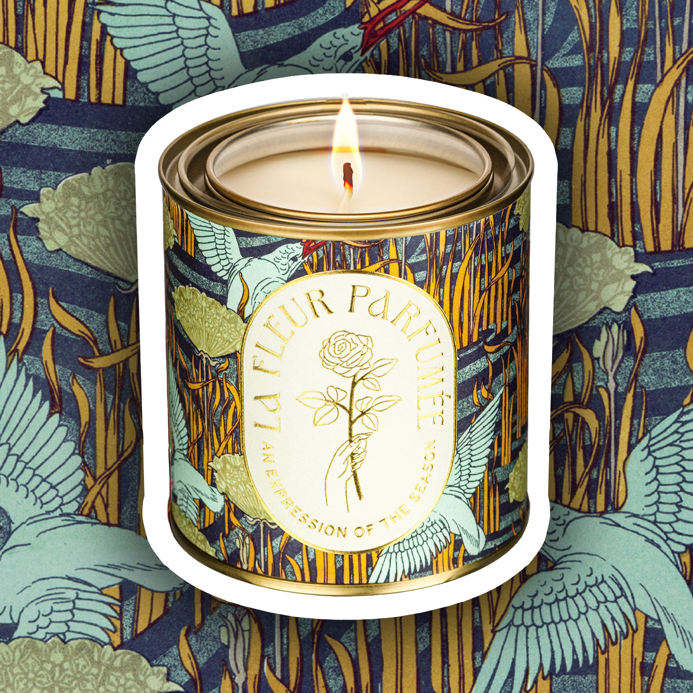 A luxury scented candle with a bold seasonal, fall, nature inspired pattern, of birds by the river with a crisp white label and gold writing that reads LA FLEUR PARFUMÉE: An Expression of the Season, and an illustration of a hand holding an elegant rose by the stem.