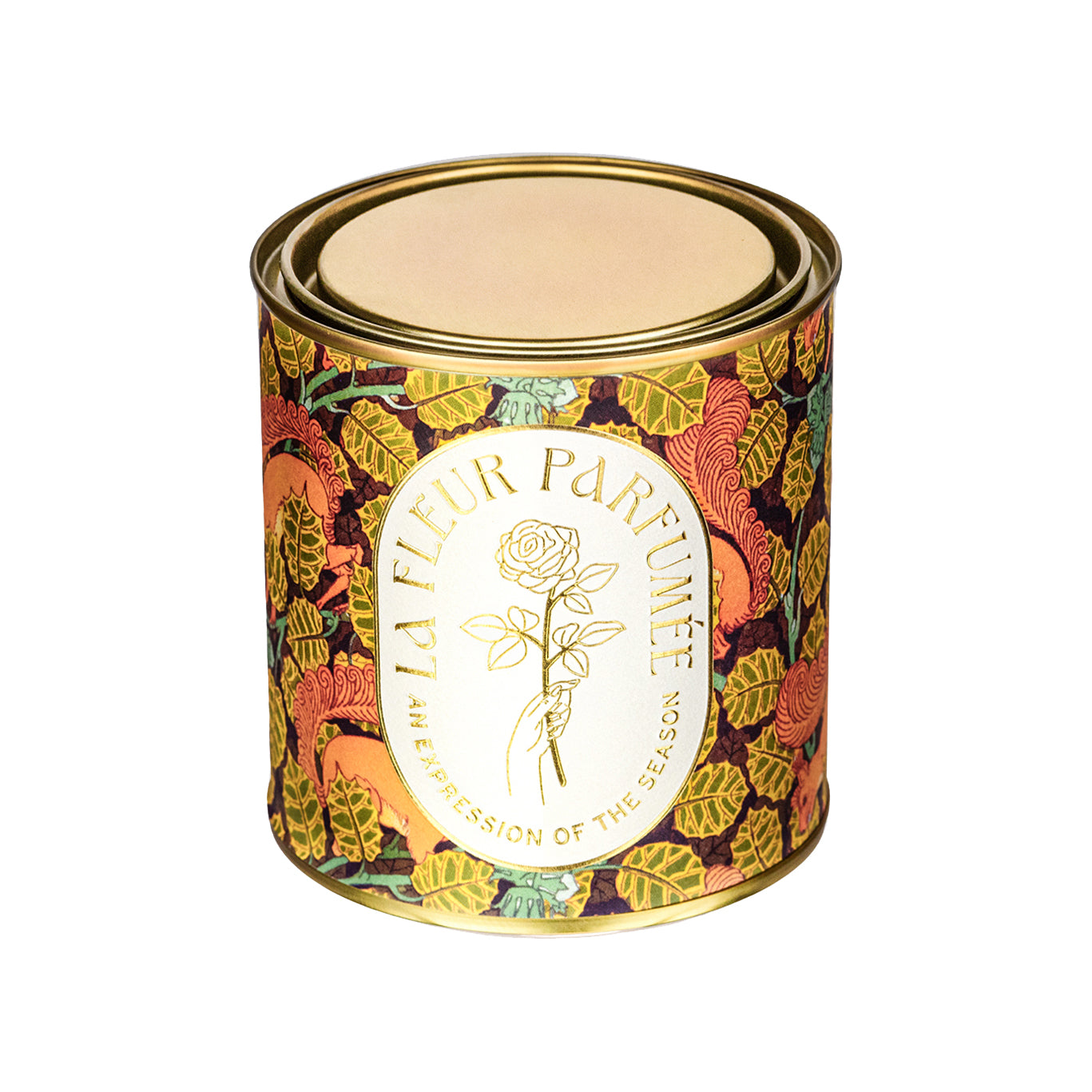 A luxury scented candle with a bold seasonal, fall, thanksgiving themed pattern, with a crisp white label and gold writing that reads LA FLEUR PARFUMÉE: An Expression of the Season, and an illustration of a hand holding an elegant rose by the stem.