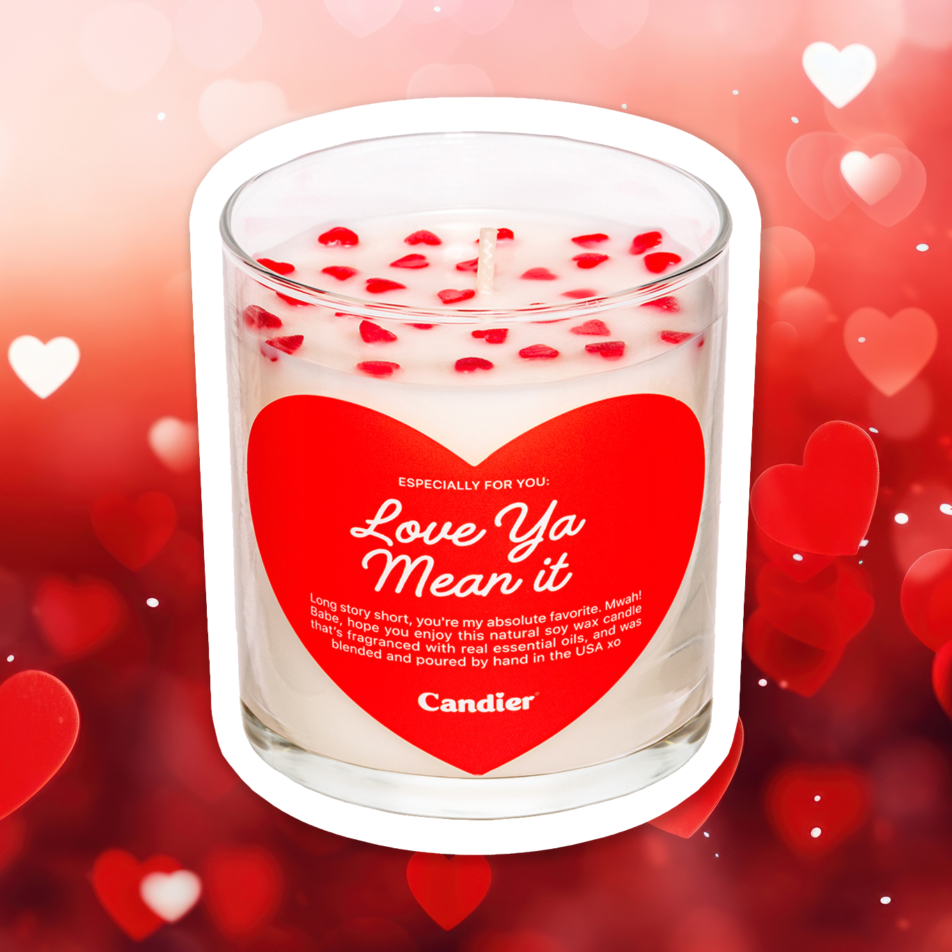 A cute scented candle with heart shaped sprinkles and a heart shaped label that reads Love Ya Mean It by Candier®, with a love heart pattern background