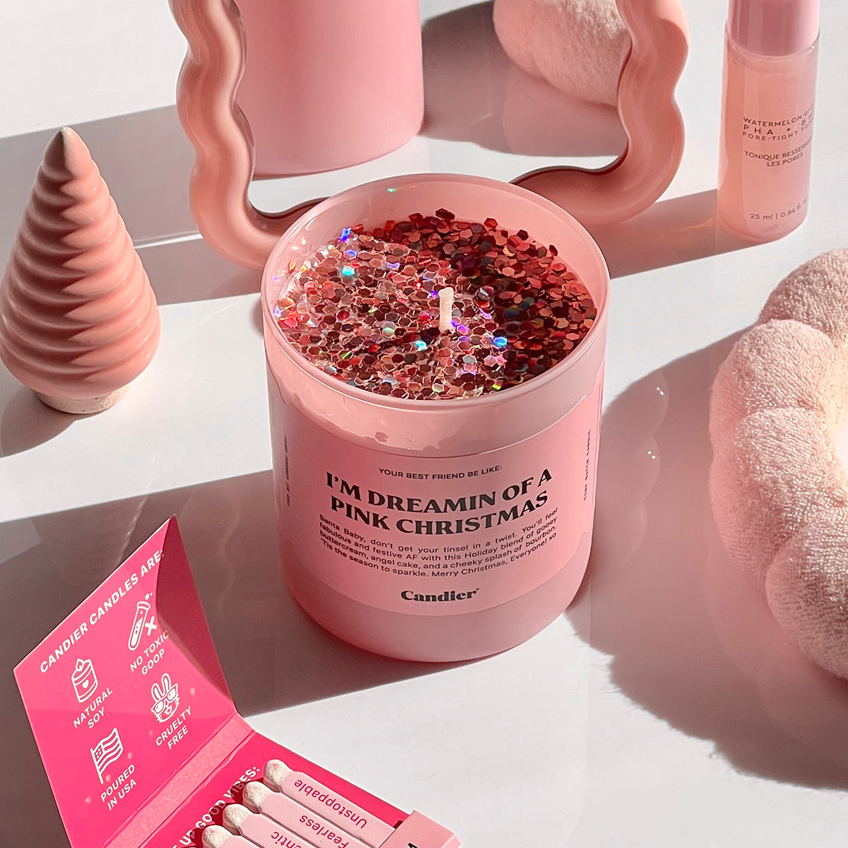 A Candier pink candle, topped with sparkling glitter, and a label that reads “I'm Dreaming Of A Pink Christmas” with cute decor