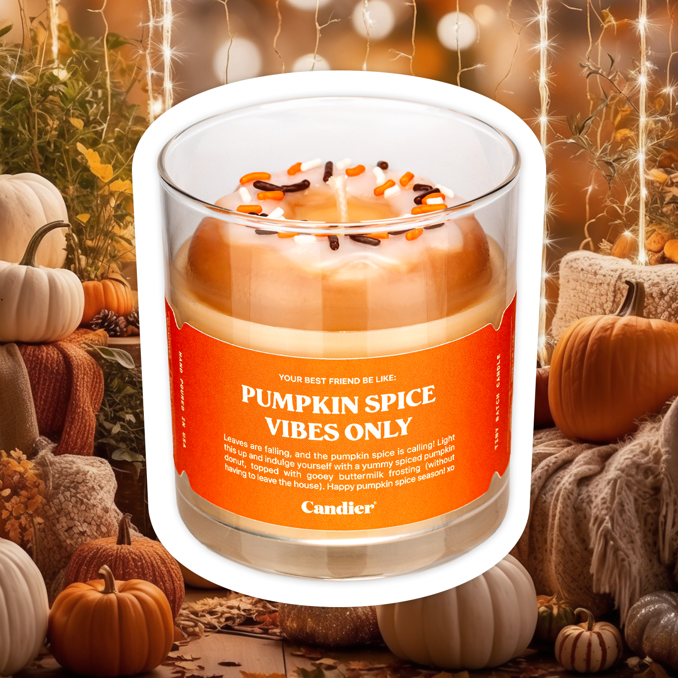 A cute fall scented candle with a wax glazed donut on top and a label that reads Pumpkin Spice Vibes Only, with a background of trendy fall decor