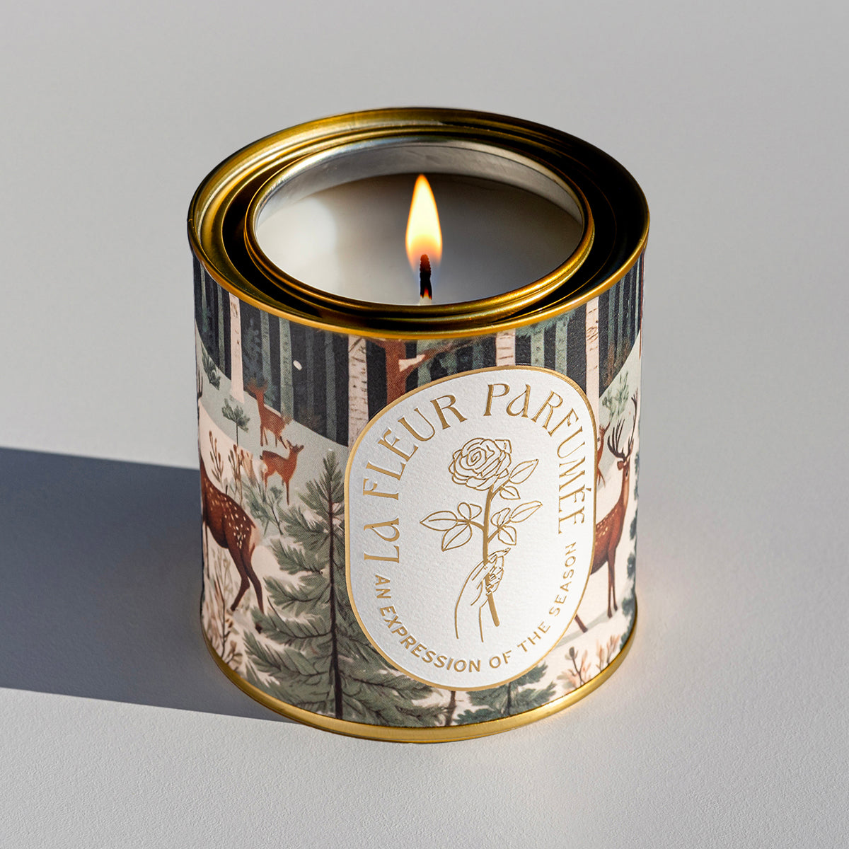 a luxury Holiday candle with beautiful artwork of deer in a snowy forest  