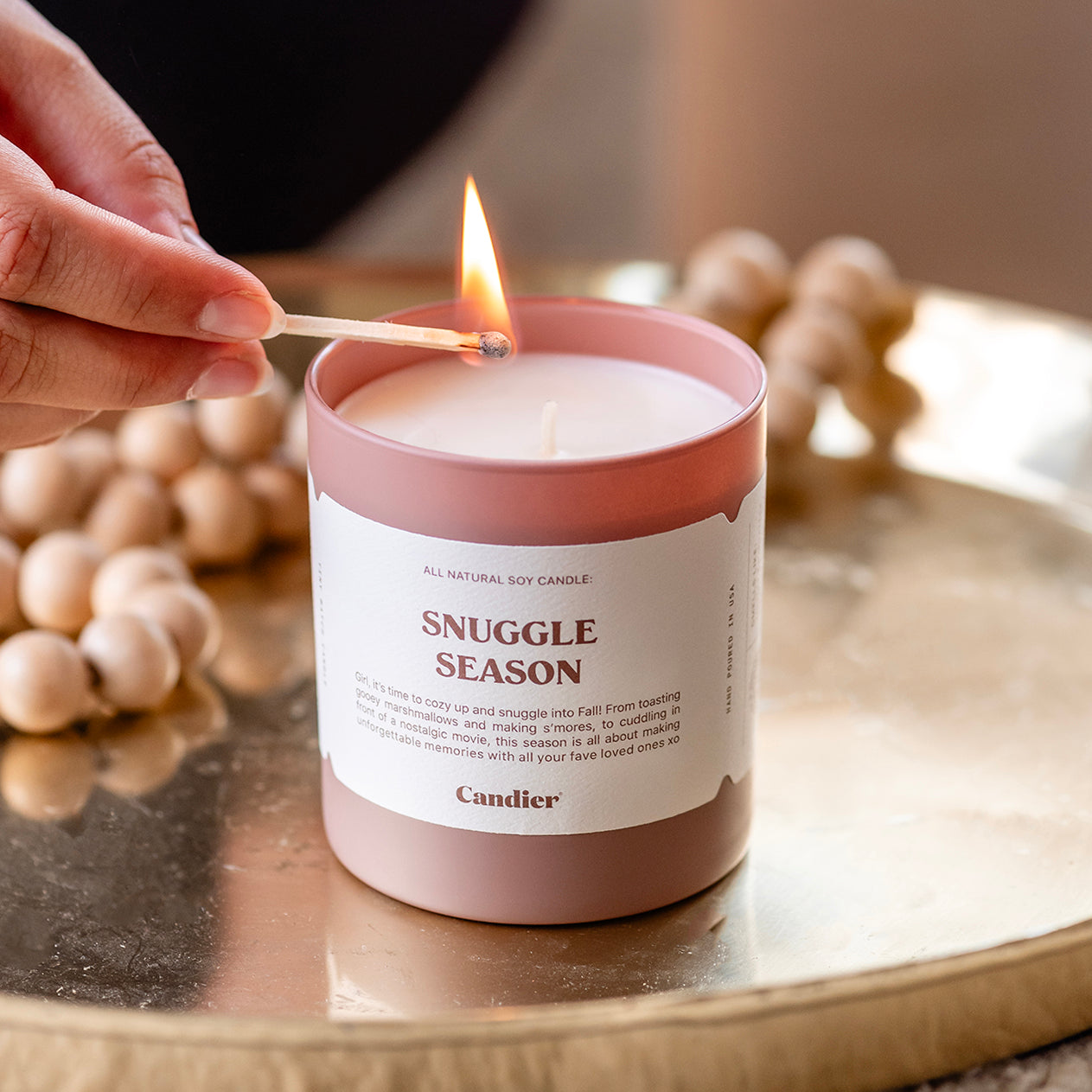 a luxury scented candle being lit with a message that reads Snuggle Season 