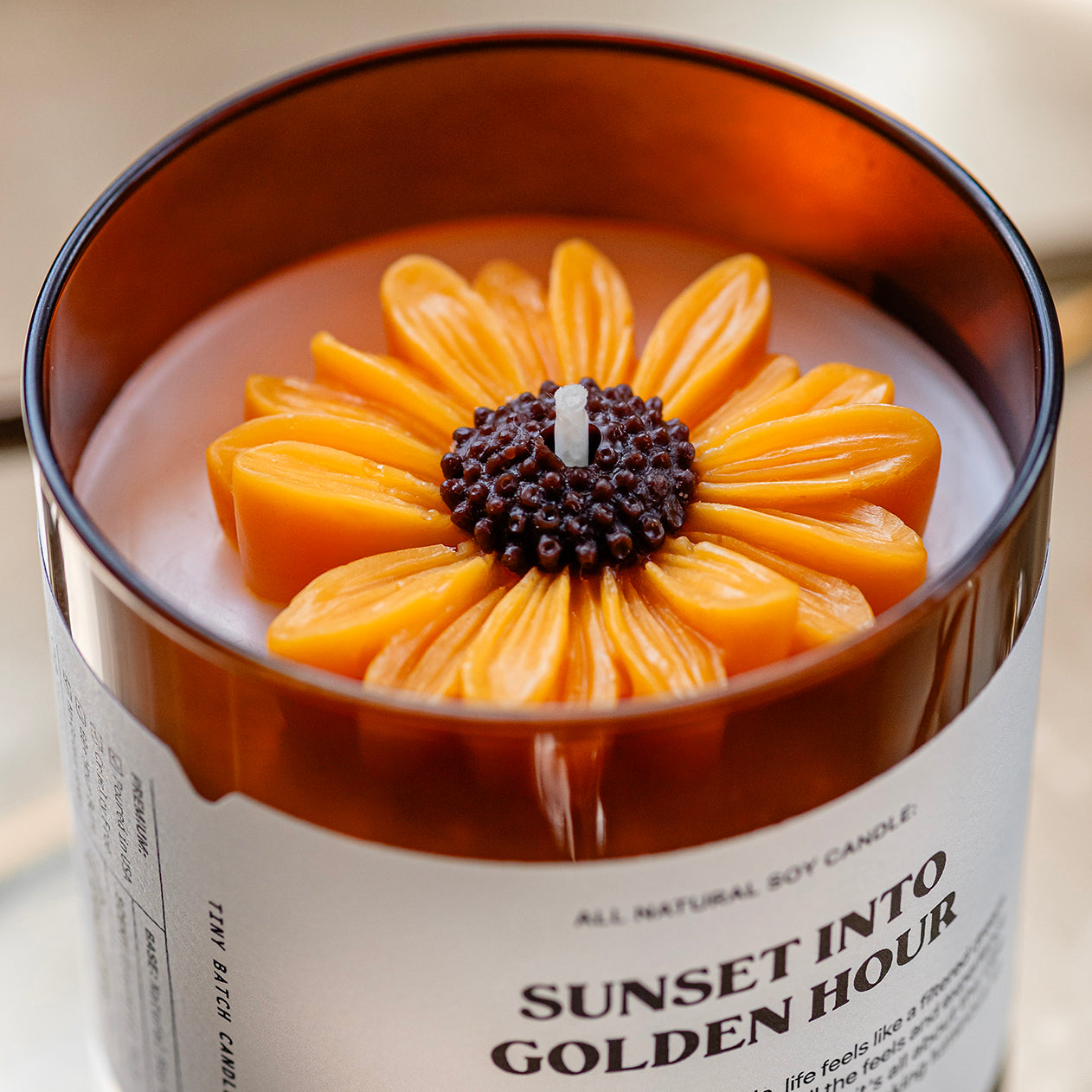 a fall scented candle topped with a molded wax sunflower