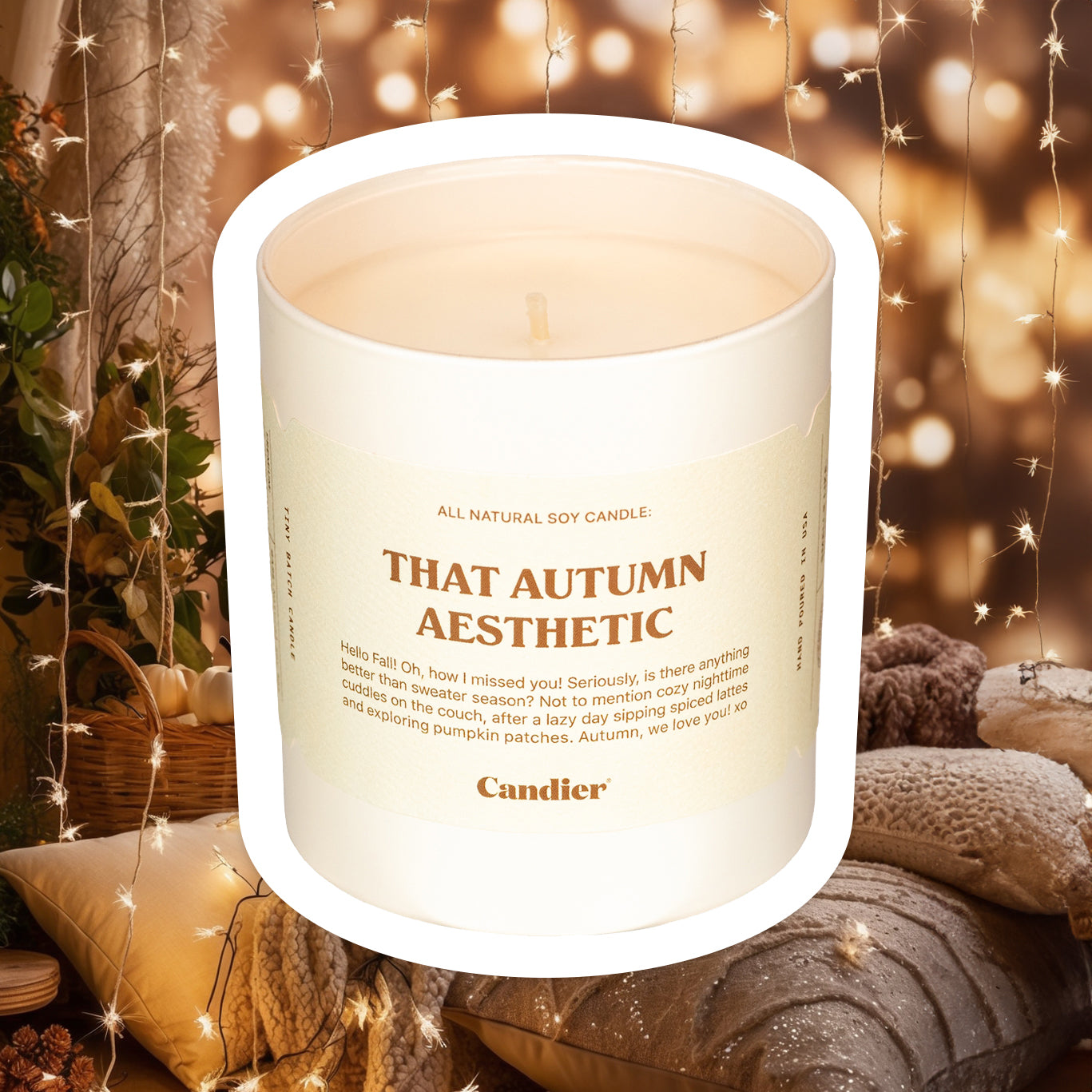 A luxe fall candle with a label that reads That Autumn Aesthetic by CANDIER, and a cozy scene of fall decor and sparkling string lights