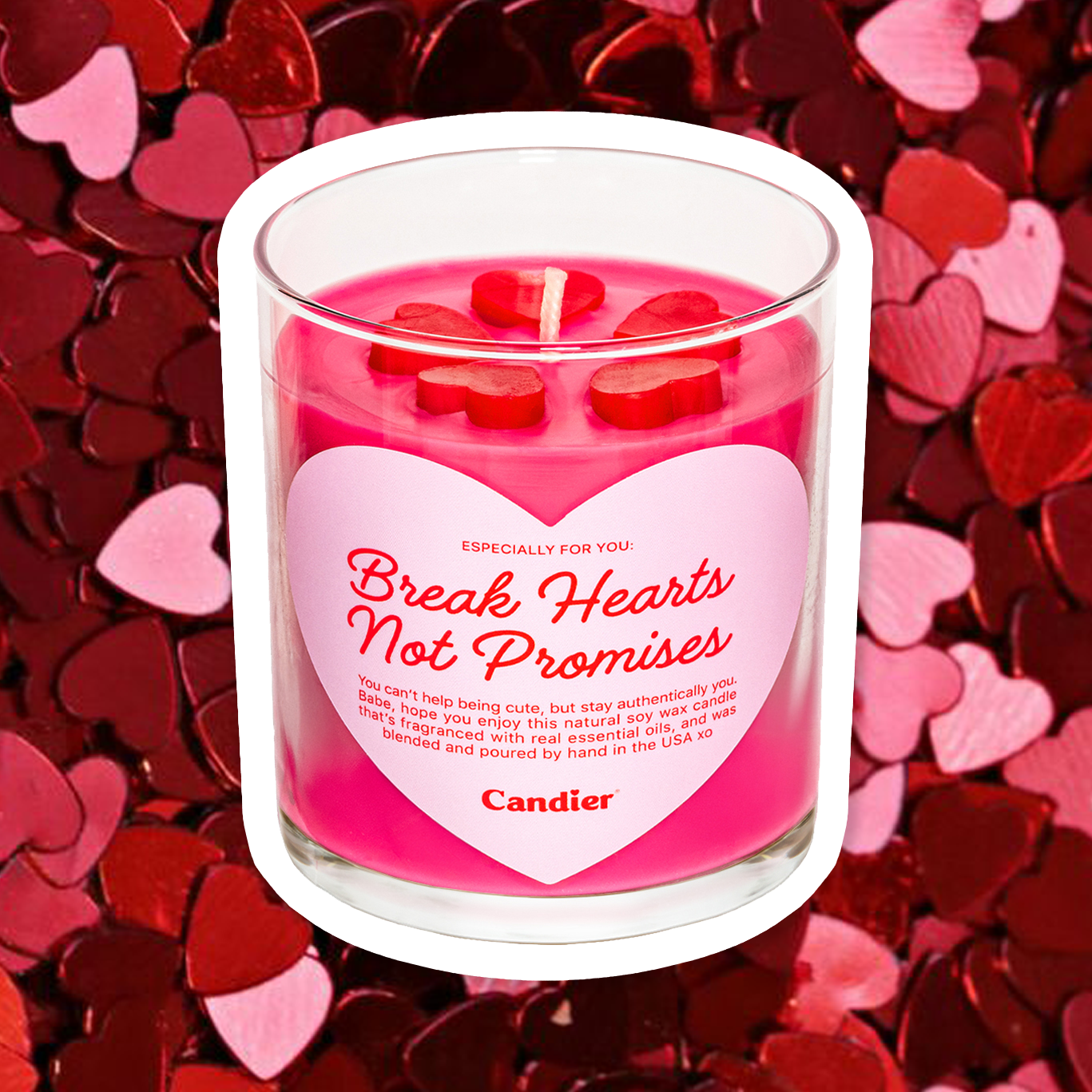 An adorable pink scented candle with red sculpted wax hearts on top, and a heart shaped label that reads Break Hearts Not Promises by Candier®, with a heart pattern background