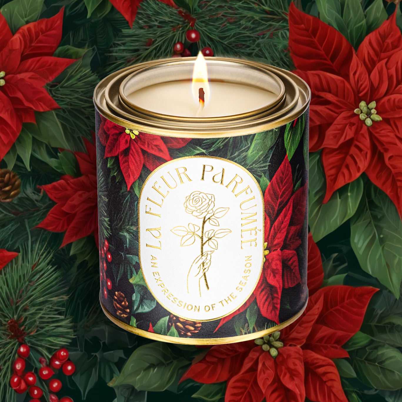 An elegant lit luxe gold-tone candle depicting a classic Christmas composition showcasing vibrant red poinsettias, sprigs of pine, and clusters of holly berries. The deep green backdrop highlights the rich crimson petals, while pinecones add a rustic holiday touch. This festive arrangement exudes timeless holiday cheer, evoking the warmth and tradition of the season